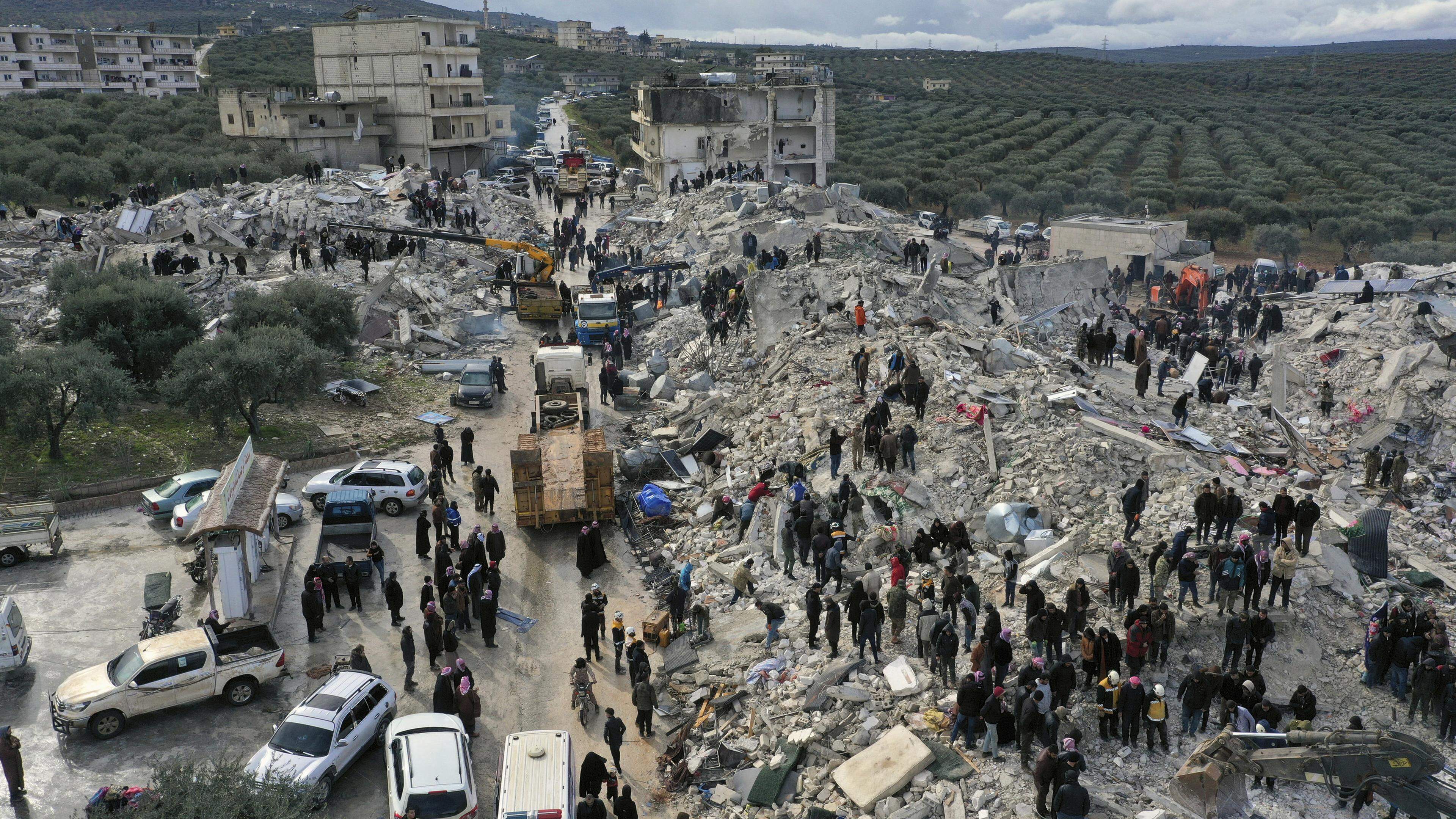 Retter und Anwohner durchsuchen im syrischen Harem nahe der Grenze zur Türkei die Trümmer eingestürzter Gebäude nach Überlebenden.