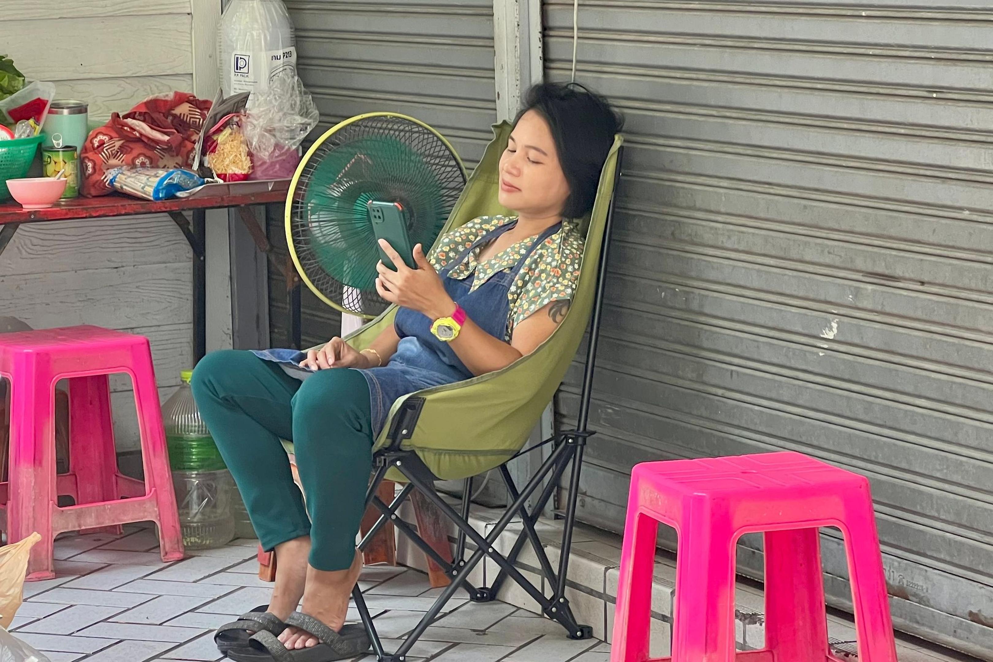 Im Schatten und mit Ventilator: Eine Frau in Bangkok versucht, sich sich abzukühlen.