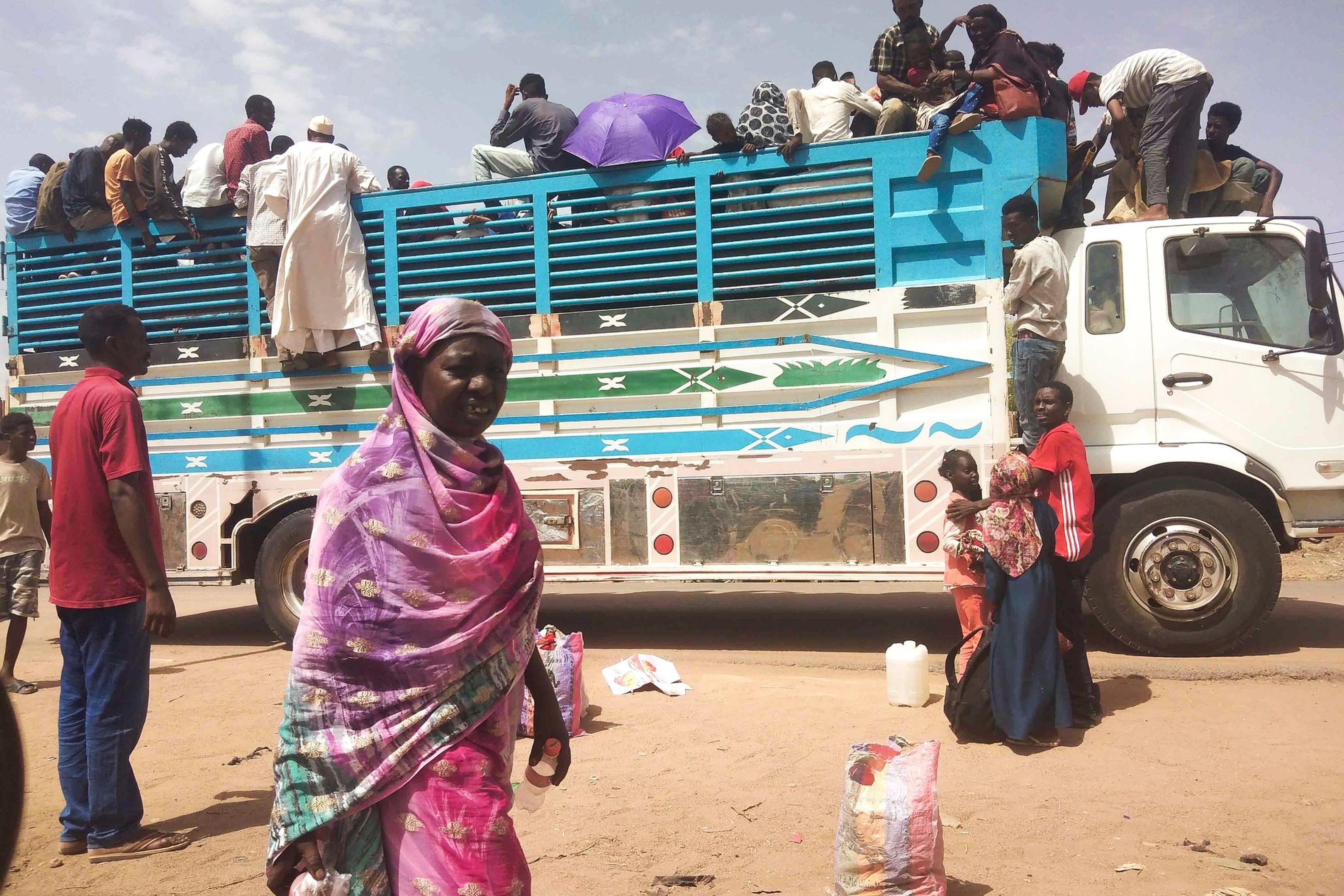 Menschen besteigen einen Lastwagen, um eine Stadt im Sudan zu verlassen.