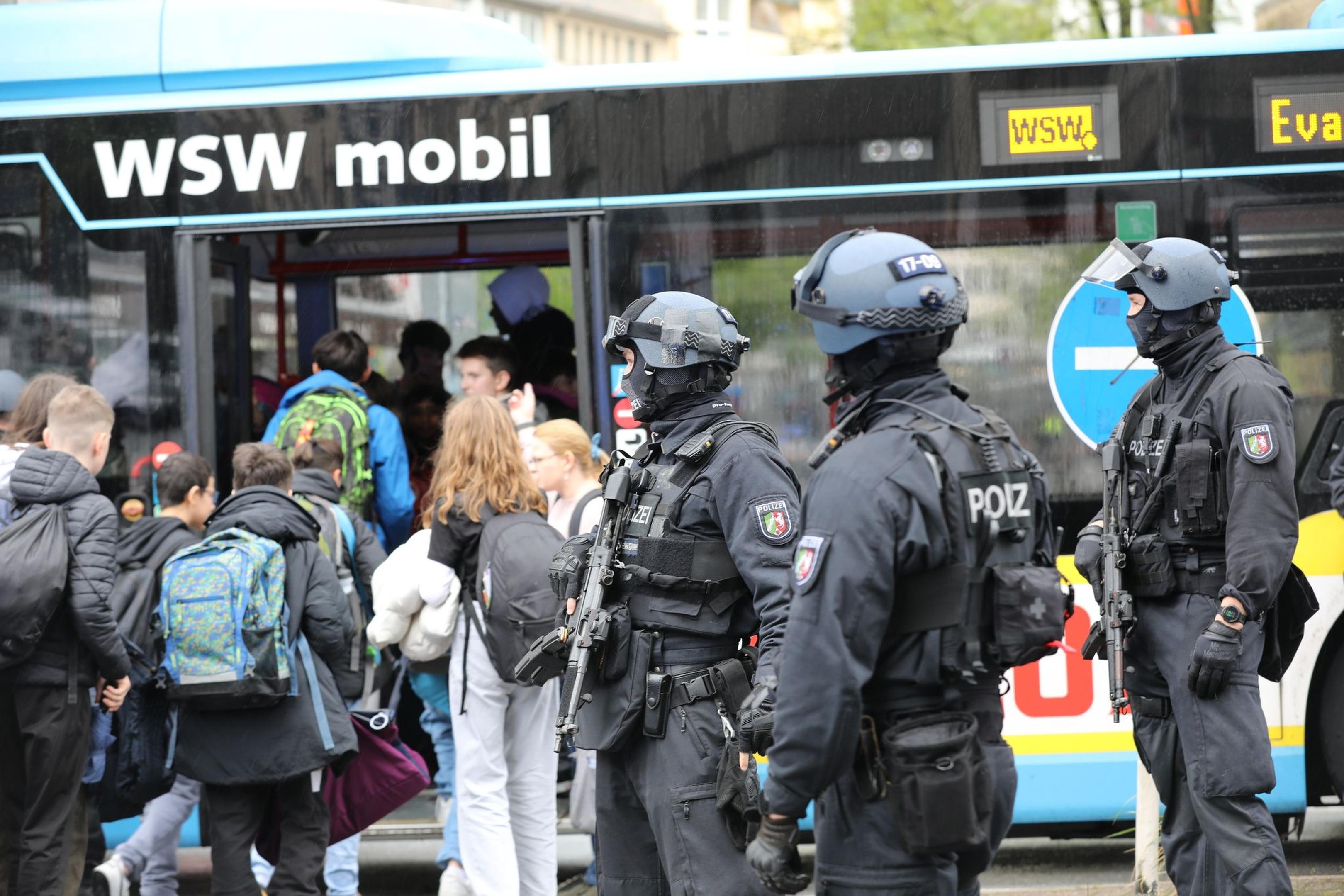 Polizisten führen Schüler aus dem Gebäude in einen Evakuierungsbus.