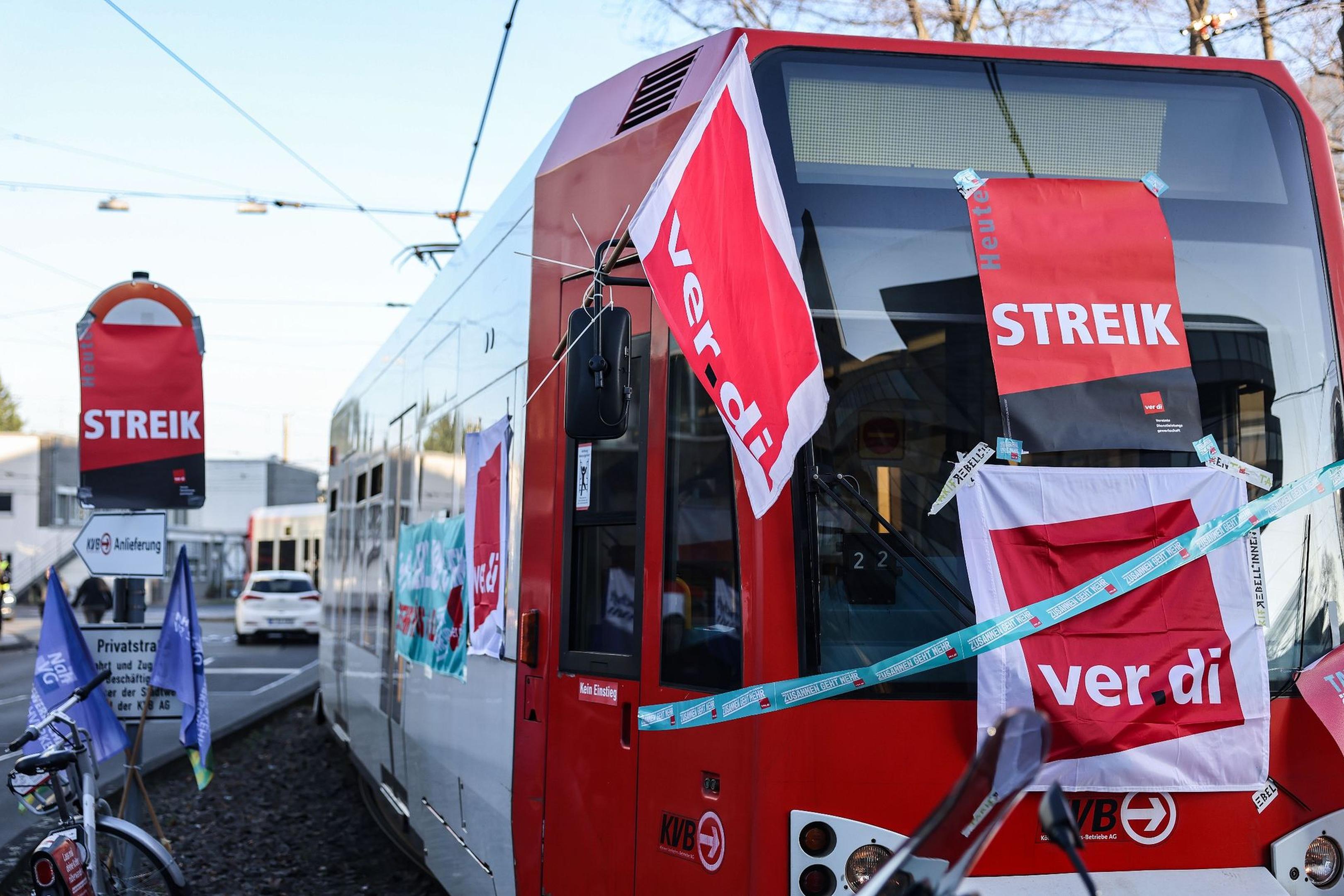 Eine mit Streik-Plakaten beklebte Straßenbahn der Kölner Verkehrs-Betriebe steht vor dem Bahndepot.